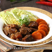 A plate of braised beef with soy sauce, sliced carrots on one side, and chopped lettuce and cabbage on the other, on a round white plate with a wooden background.