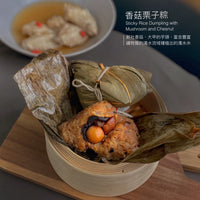 A wooden tray holds a basket of mushroom and chestnut dumplings wrapped in leaves, and in the background, you can see a plate with food in broth and a text overlay that reads “Mushroom and chestnut dumplings: mushroom and chestnut dumplings.”