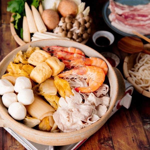 Traditional Pickled Cabbage Pork Hot Pot Soup filled with shrimp, sliced pork, mushrooms, tofu and veggies ready to be cooked at the table with noodles and dipping sauce on the side.